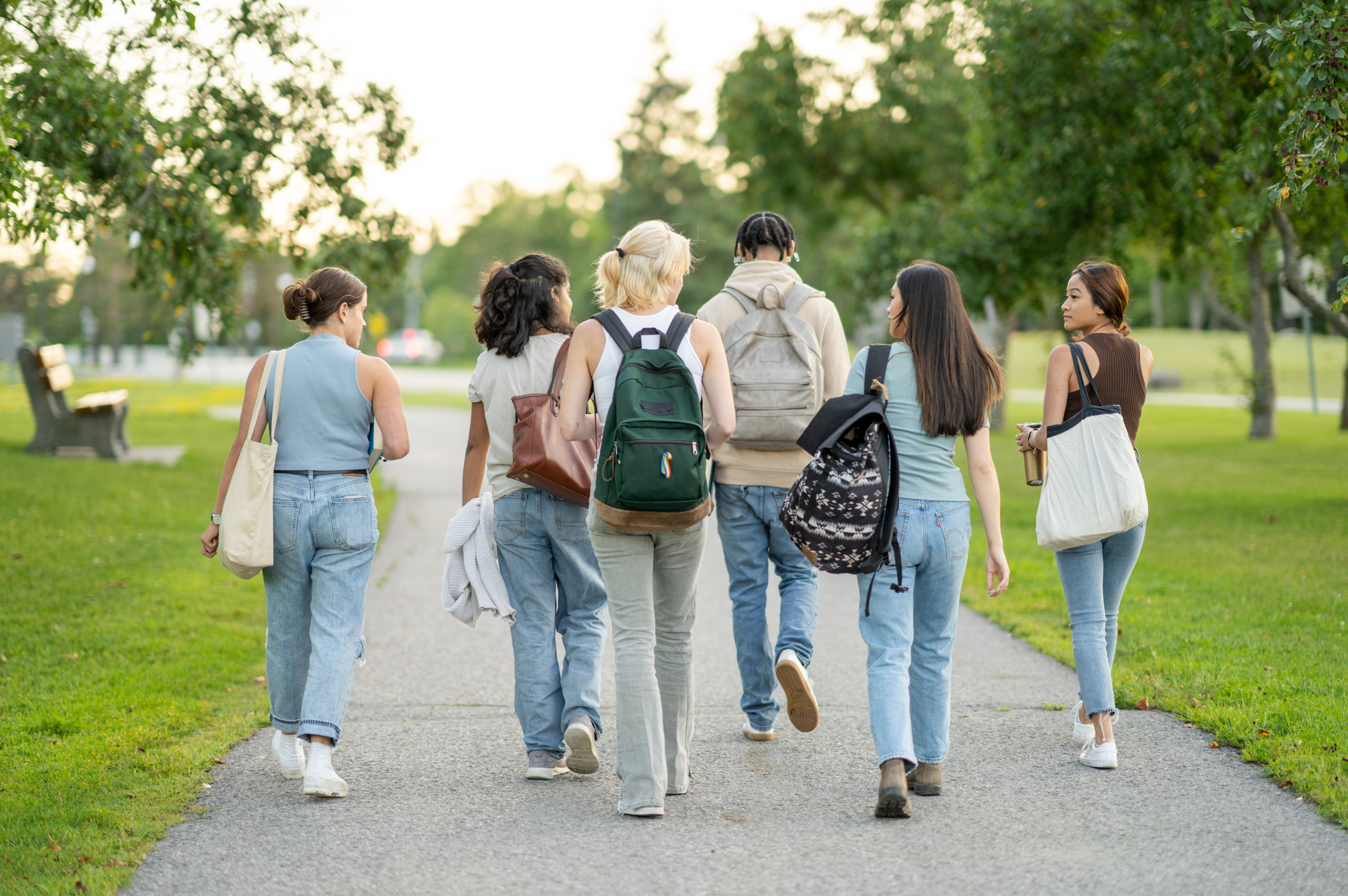 A diverse group of students walk down a campus path.