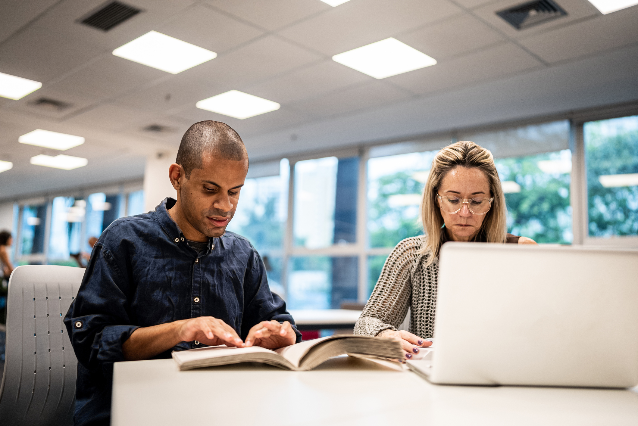 Mid adult man visually impaired man reading a braille book at university