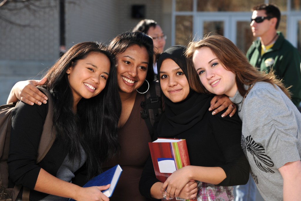 Group of diverse students in a group with others in the background