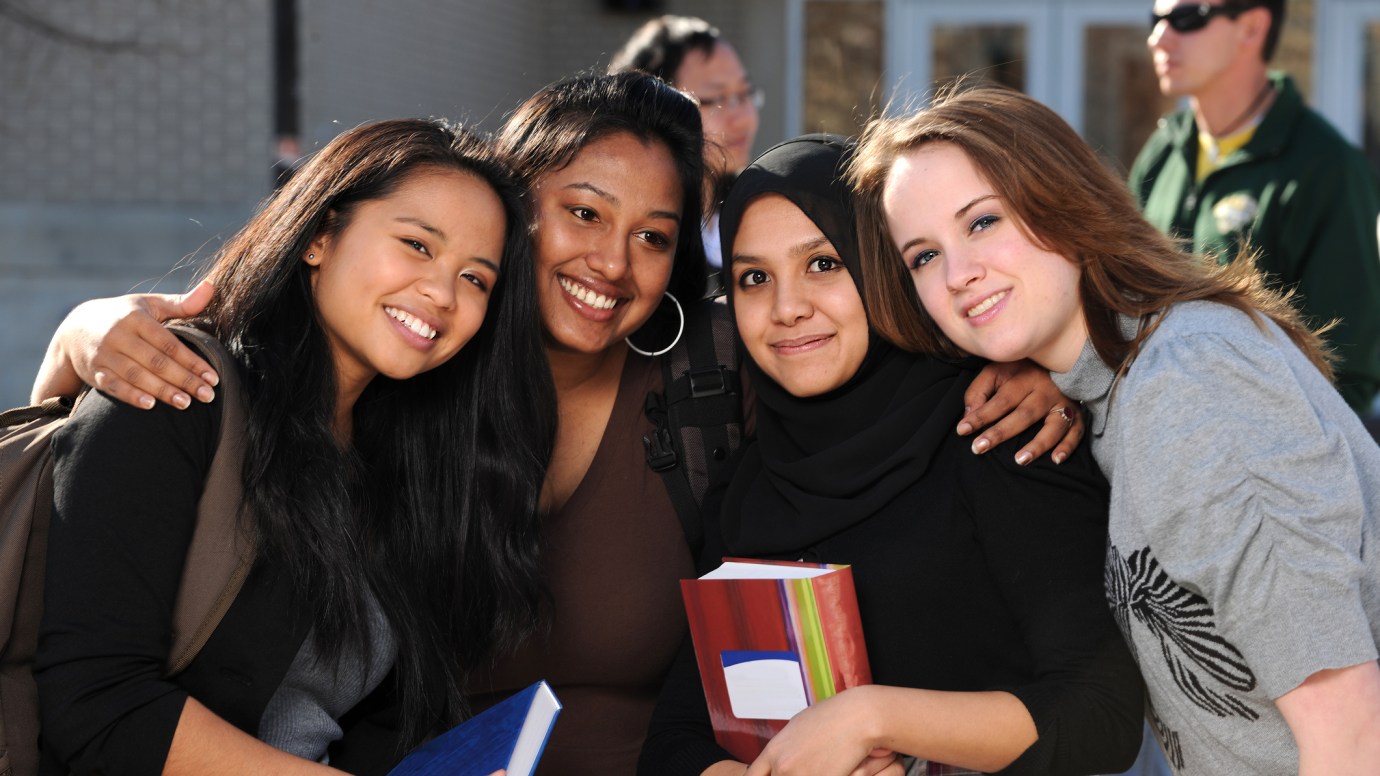 Group of diverse students in a group with others in the background