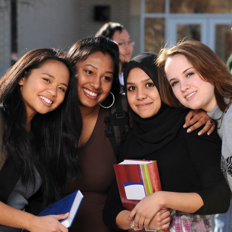 Group of diverse students in a group with others in the background