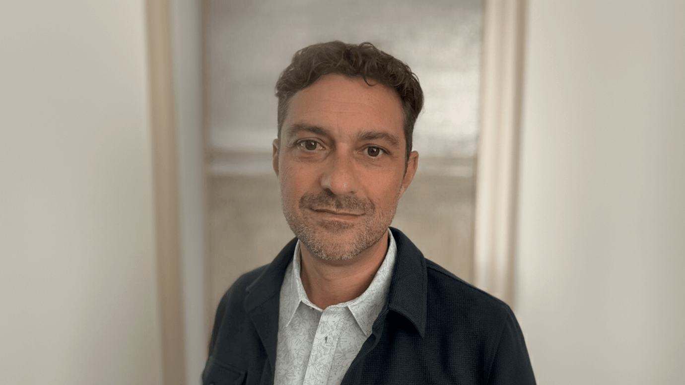 Ken LaOrden, a light-skinned man with brown hair and stubble, wearing a dark blue jacket over a gray collared shirt.