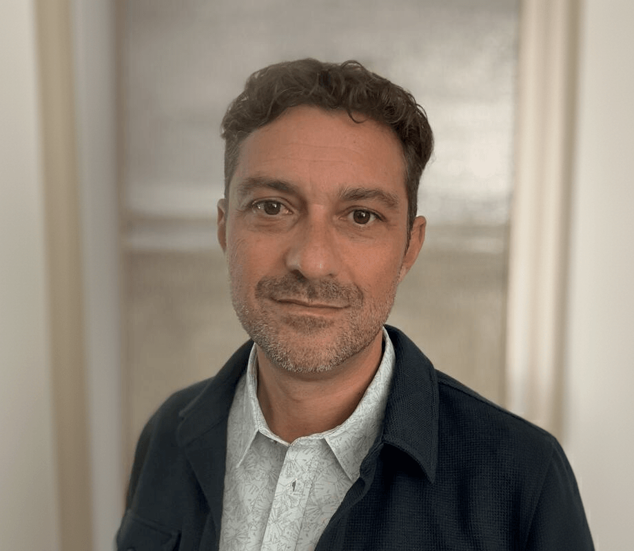 Ken LaOrden, a light-skinned man with brown hair and stubble, wearing a dark blue jacket over a gray collared shirt.